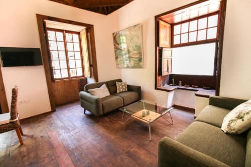Amplio salón en Casa 1820, apartamento rural en Santa Cruz de la Palma, con sofás, mesa de cristal y suelos de madera