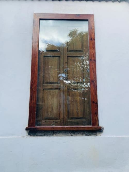 Puertas dobles de madera con marco rojo en Casa 1820 de paredes blancas, reflejando las vistas de montaña de Santa Cruz de la Palma
