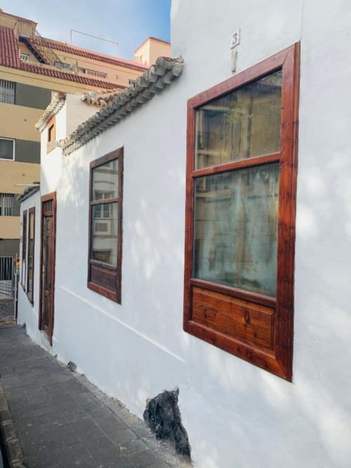 Casa 1820 de paredes blancas en Santa Cruz de la Palma con ventanas enmarcadas en rojo y arquitectura tradicional con vistas al jardín