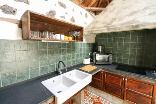 Cocina rústica en Casa 1820, La Palma rural, con azulejos verdes, pileta blanca, encimera oscura y muebles de madera.