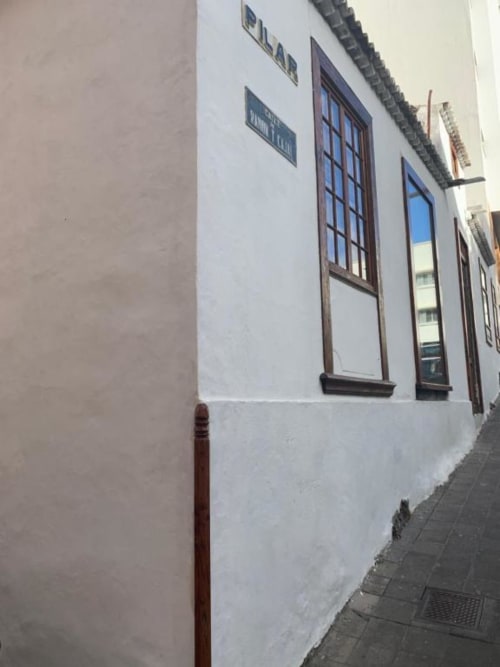 Exterior con muros blancos de Casa 1820, apartamento rural en La Palma, Santa Cruz de la Palma, con ventanas de marcos oscuros y puerta roja