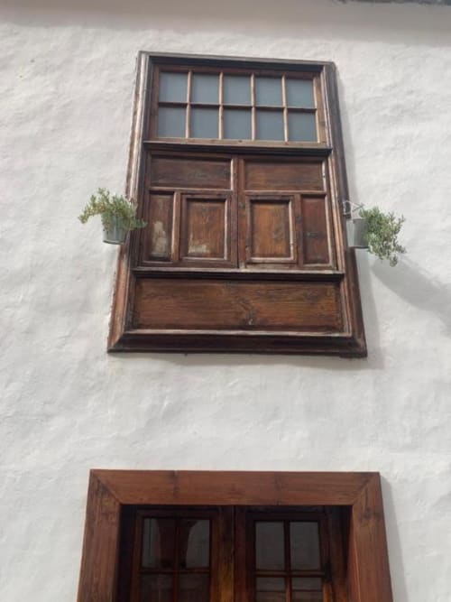 Fachada histórica con ventana y puerta de madera de Casa 1820 en Santa Cruz de la Palma, muros blancos y plantas en macetas