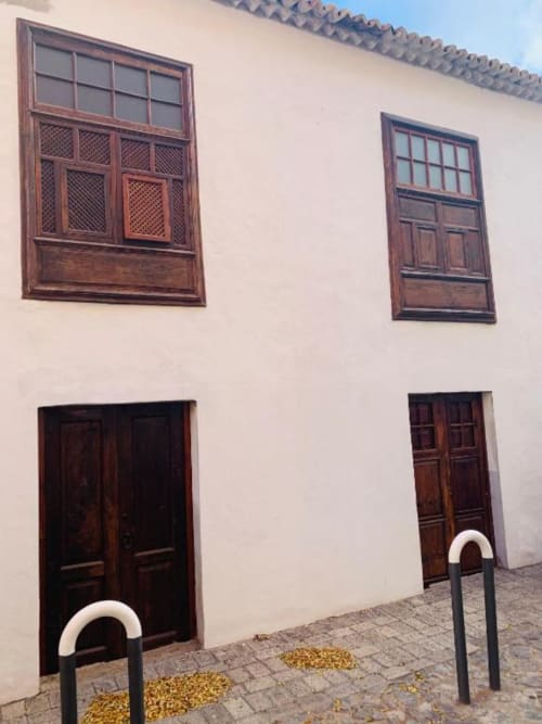 Fachada encalada de la Casa 1820 en Santa Cruz de la Palma con puertas de madera, ventanas ornamentales y aparcabicicletas en patio empedrado