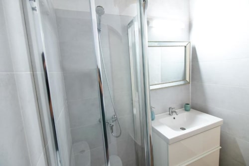 Baño moderno con cabina de ducha, lavabo blanco, espejo y paredes azuleadas en el apartamento rural Casa 1820 de Santa Cruz