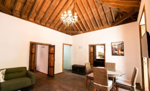 Amplia sala de estar en Casa 1820 Rural La Palma con vigas de madera, lámpara de araña, sofá, mesa de comedor y puertas de madera