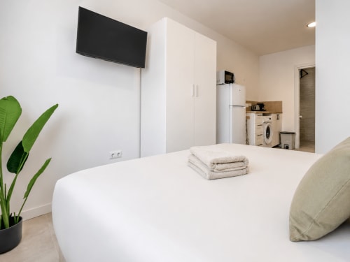 Moderna suite accesible en Studios Sanchis, Alicante con cama, TV mural, armario, cocina americana y zona verde