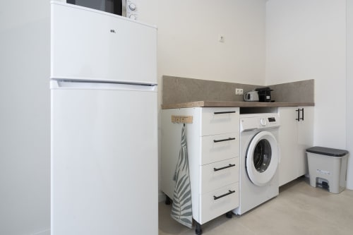 Área compacta de lavandería y cocineta en habitación Studio accesible de Studios Sanchis, Alicante con lavadora, horno y
