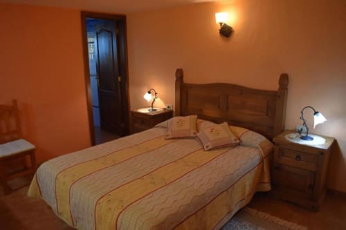 Acogedor dormitorio en Villa Las Flores con cama de madera, paredes naranja cálidas y lámparas de mesita en Tijarafe, La Palma