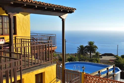 Terraza de Villa Las Flores con piscina azul, vistas al océano y arquitectura amarilla en Tijarafe, La Palma