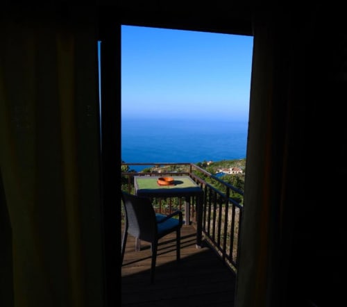 Vista desde la terraza de Villa Las Flores en Tijarafe, La Palma: balcón con silla frente al océano azul y la costa