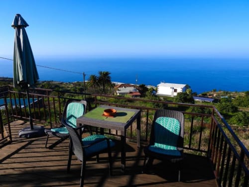 Terraza con sillas turquesas con vistas al océano y el paisaje de La Palma en Villa Las Flores