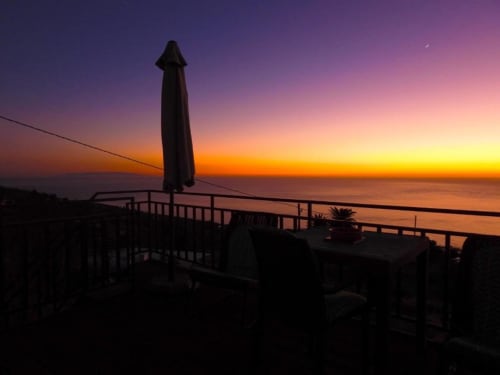Atardecer sobre el océano desde la terraza de Villa Las Flores en Tijarafe, La Palma, con silueta de sombrilla