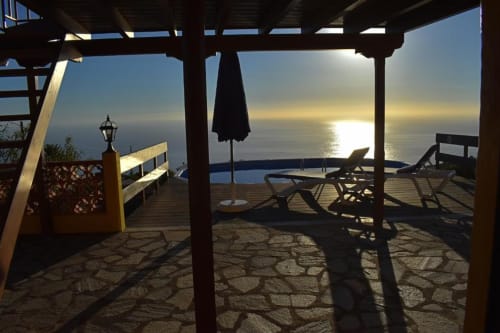 Terraza de Villa Las Flores al atardecer con vista al océano en Tijarafe, La Palma, con tumbonas y pérgola