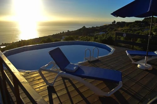 Vista al atardecer del océano desde la terraza de Villa Las Flores con piscina, tumbonas y costa mediterránea en Tijarafe, La Palma