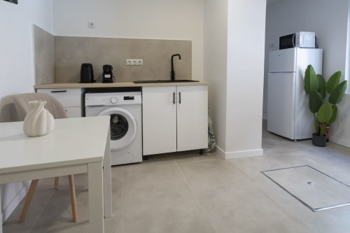 Kitchenette moderno en Studios Sanchis Alicante con lavadora, refrigerador y zona de comedor
