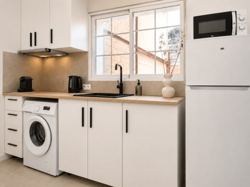 Cocina moderna en estudio de Studios Sanchis en Alicante con muebles blancos, encimera de madera, lavadora y