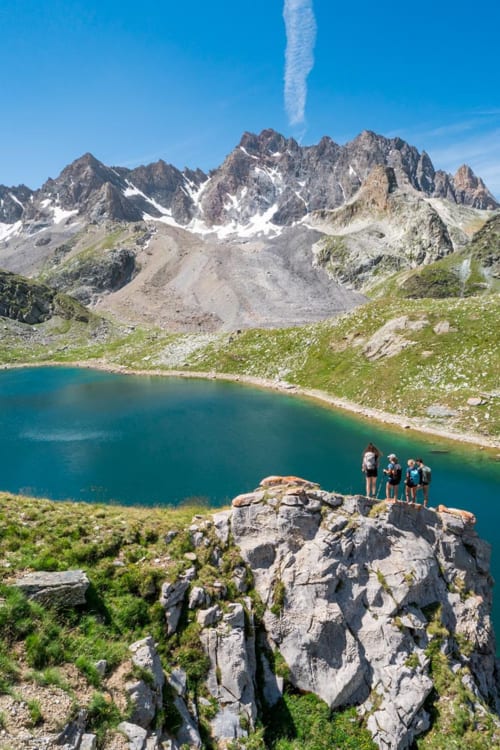Randonneurs sur un pic rocheux dominant un lac alpin turquoise près de la Maison d'Hôtes Les Méans, Meolans-Revel, France