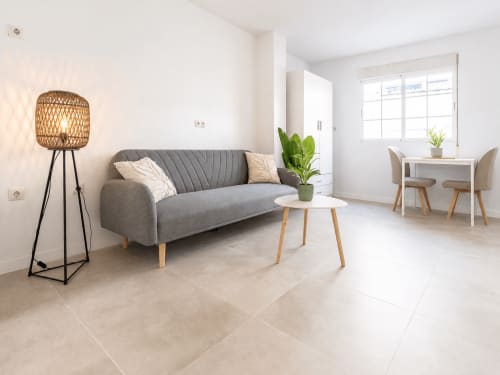 Moderno apartamento estudio en Hotels Sanchis Alicante con sofá gris, lámpara tejida y balcón luminoso con vistas a la piscina