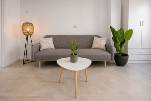 Sala de estar moderna en Studios Sanchis Alicante con sofá gris, mesa de café blanca y plantas en macetas