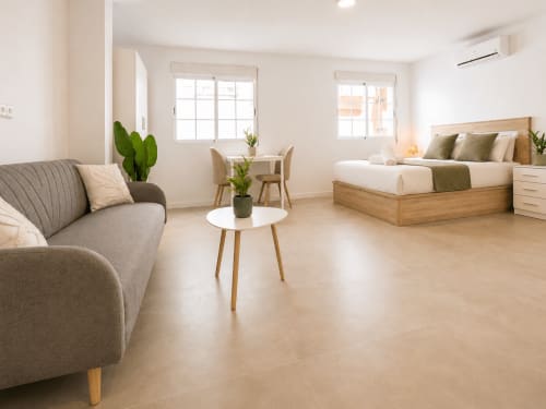 Estudio moderno con sofá, zona de comedor y cama de madera en Studios Sanchis, Alicante, España