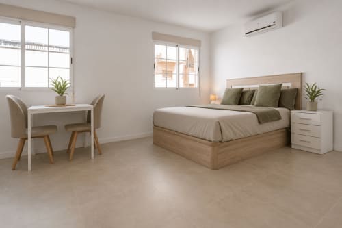 Moderno estudio en Studios Sanchis, Alicante, con cama de madera, escritorio y ventanales luminosos con vistas a la piscina