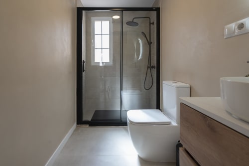 Baño moderno en el hotel Studios Sanchis, Alicante con ducha a ras de suelo, inodoro, lavabo y suelos de cerámica