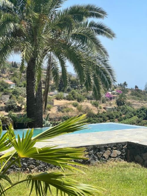 Terraza con piscina privada, palmeras y vistas a las colinas en villa Nexus, Tijarafe, La Palma