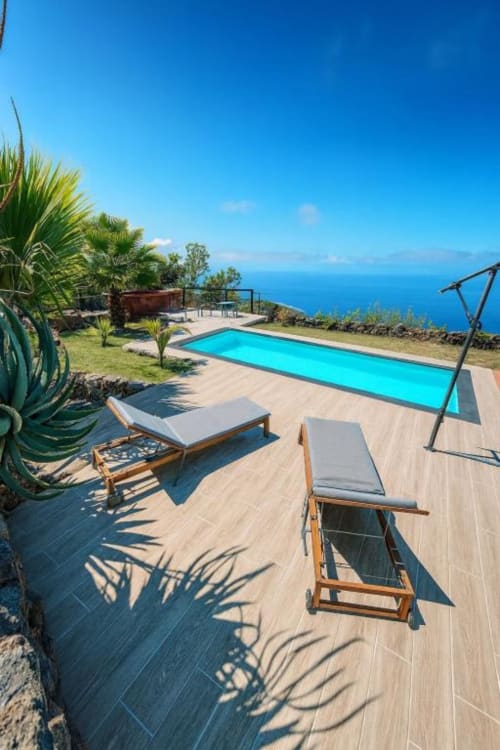 Villa de lujo con piscina de aguas turquesas, tumbonas, vistas al océano y plantas tropicales en La Palma, España