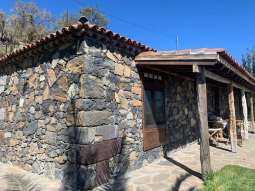 Villa de piedra Rural La Palma con tejado de barro, porche de madera y vistas a las montañas en El Pinillo, España