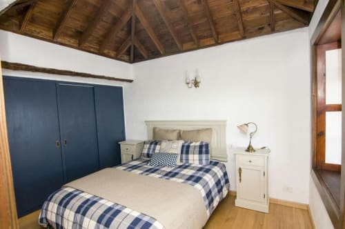 Dormitorio espacioso en Villa Awara de Rural La Palma con armario azul marino, mesitas blancas y ropa de cama a cuadros azules