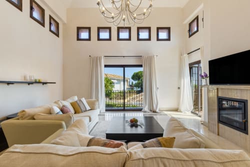 Bright modern living room in Benalmádena villa with cream sofas, fireplace, ocean views through glass doors, and terrace