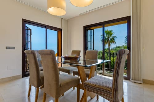 Modern dining room with terrace views at Ayma Villa Cielo y Mar in Benalmádena, featuring glass table and upholstered chairs