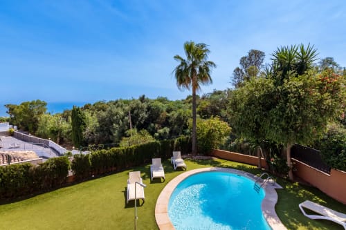 Luxury villa pool overlooking Mediterranean Sea in Benalmádena with lounge chairs, manicured garden, and palm trees