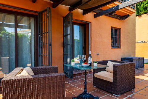 Terracotta patio with wicker seating and glass table at Ayma Villa Cielo y Mar, Benalmádena