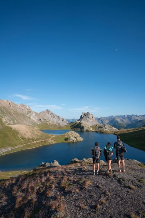 Trois randonneurs admirent les lacs alpins entourés de pics rocheux près de Maison d'Hôtes Les Méans à Meolans-Revel