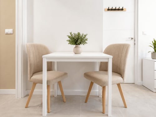 Moderna sala de estudio en Studios Sanchis Alicante con mesa blanca, sillas beige y planta en maceta