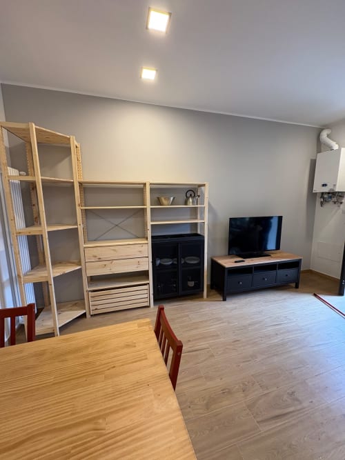Soggiorno di lusso a Milano con scaffalature in legno, mobile TV, tavolo da pranzo e vista sulla città