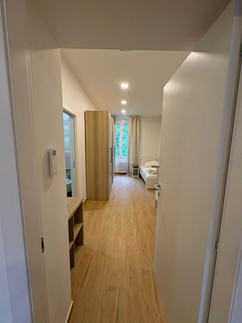 Moderno corridoio nell'appartamento di Milano con pavimenti in legno, pareti bianche, illuminazione a incasso e accesso alla camera da letto presso urban ESCAPE