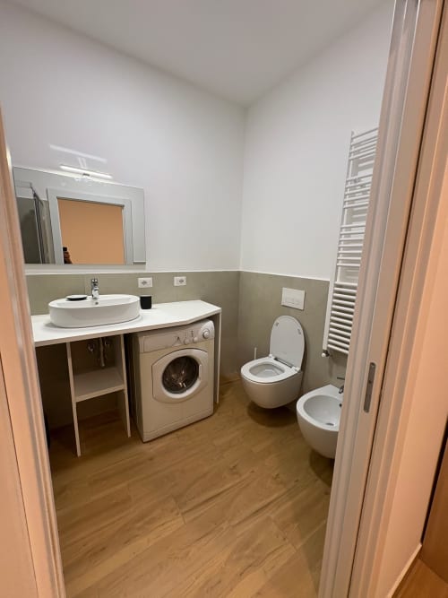 Bagno moderno in appartamento milanese con wc, bidet, lavabo ovale, lavatrice, scaldasalviette e finiture bicolore