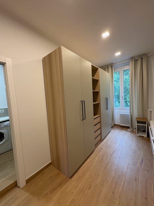 Elegante guardaroba moderno in camera da letto spaziosa con pavimento in legno e luce naturale