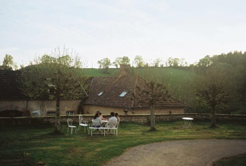 Des clients dînent en plein air au Château de Vaux Morvan, un gîte français à Étang sur Arroux, entourés de jardins verdoyants