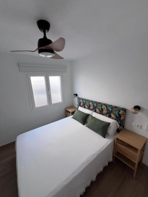 Habitación moderna en El HierroStay Apartments con cama queen, ventilador de techo y ventana con vista a la ciudad