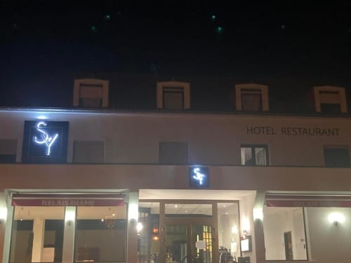 Hôtel Restaurant Le S'Y storefront at night in Seingbouse, France with illuminated neon sign and glass entrance doors