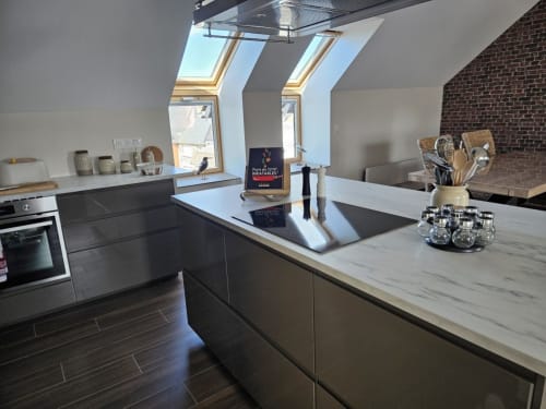Cuisine contemporaine de l'appartement Cap à l'Ouest au gîte Le Clos De La Côte D'émeraude, avec meubles sombres et plan de travail en marbre