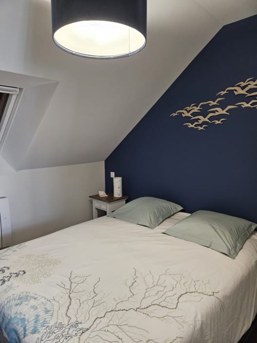 Chambre moderne de l'appartement Cap à l'Ouest au Clos De La Côte D'émeraude, avec mur d'accent bleu marine et décoration d'oiseaux volants
