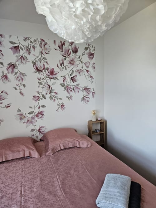 Chambre douillette au Clos De La Côte D'émeraude avec papier peint floral violet, literie rose, plafonnier blanc et boiseries