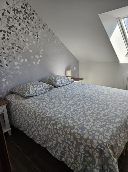 Chambre mansardée moderne au Clos De La Côte D'émeraude à Saint-Benoît-des-Ondes avec literie motifs et fenêtre de toit