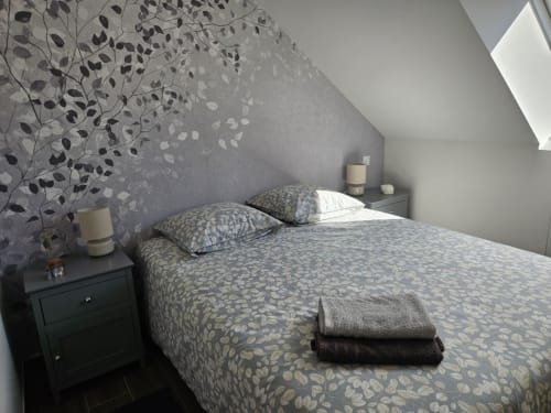 Chambre mansardée cosy au Clos De La Côte D'émeraude à Saint-Benoît-des-Ondes avec literie à motifs et papier peint fleuri