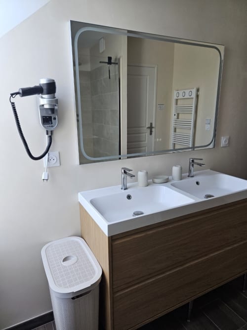 Salle de bain moderne avec double vasque, grand miroir et équipements à l'appartement Le Clos De La Côte D'émeraude B&B