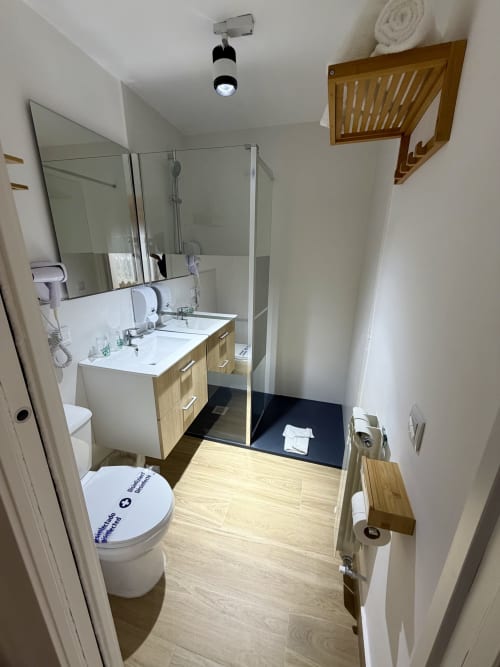 Modern bathroom with double sink, wooden vanity, walk-in shower, and toilet at Complejo Turístico Retiro del Teatro, Almagro